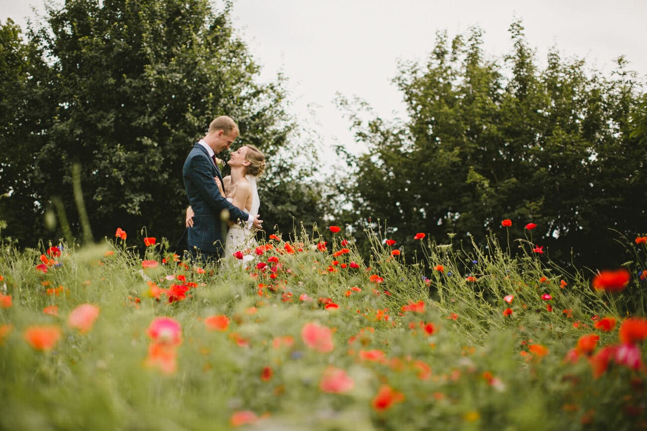 bride and groom in poppy field in suffolk
