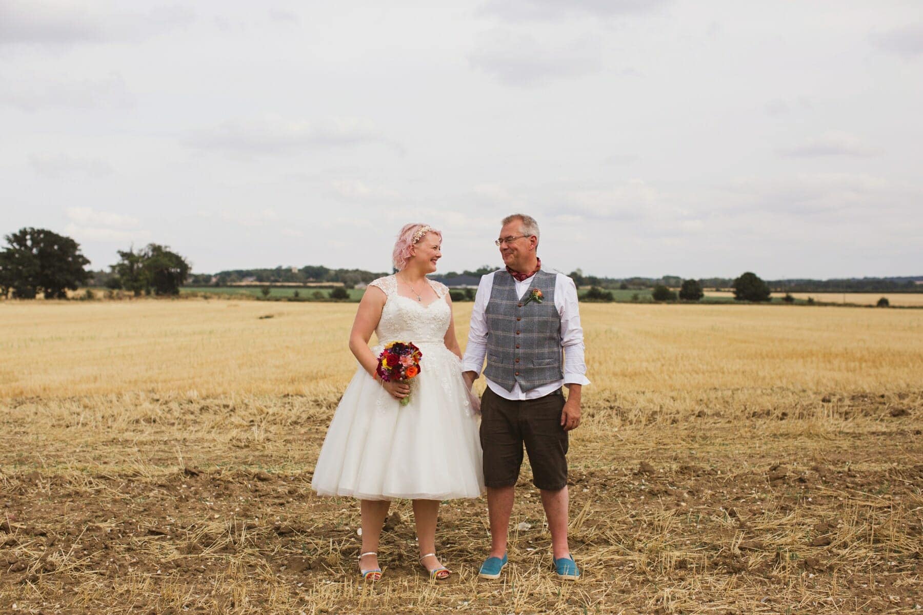bride and groom standing in a corn field in suffolk