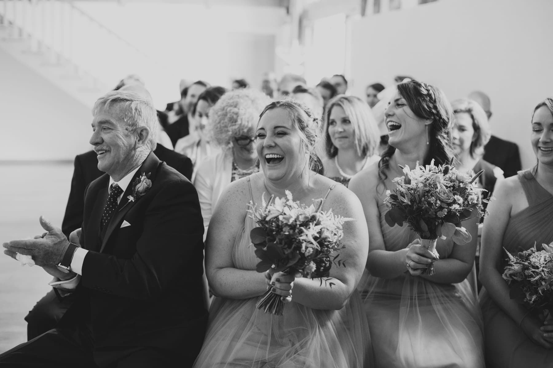 bruisyard hall and barn wedding ceremony guests laughing