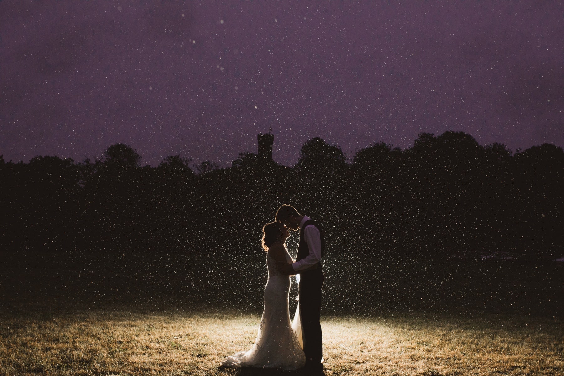 bride and groom in field in the rain