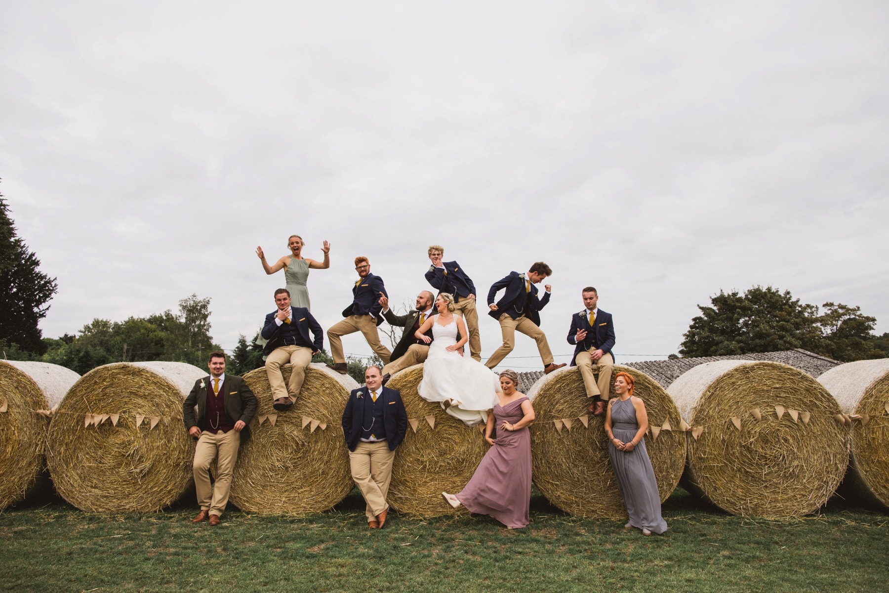 bridal party climbing on hay bales for a photo