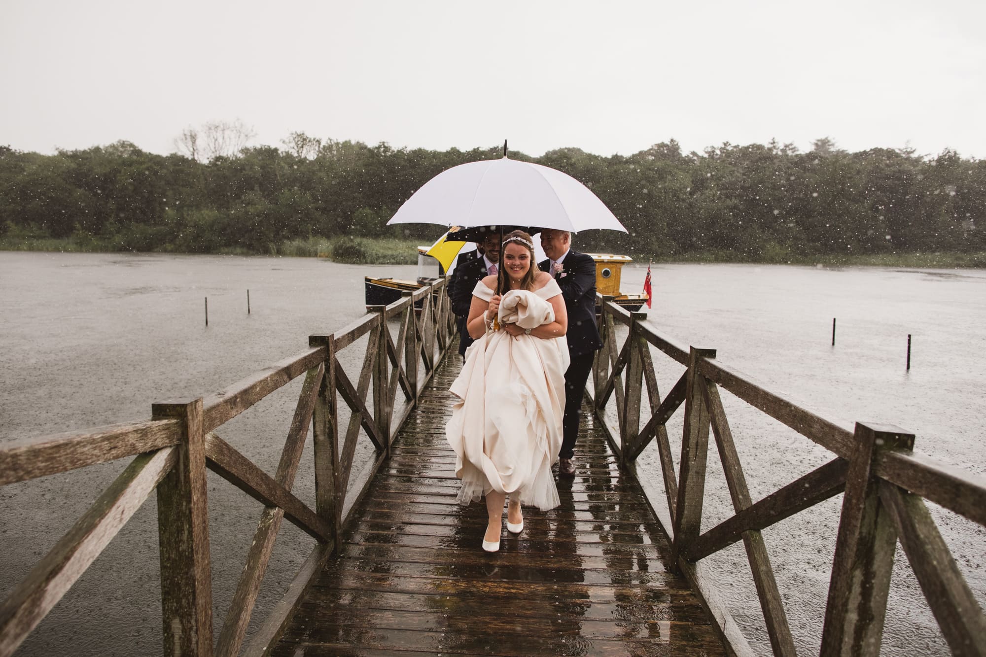bride and groom walking on the jetty in the rain