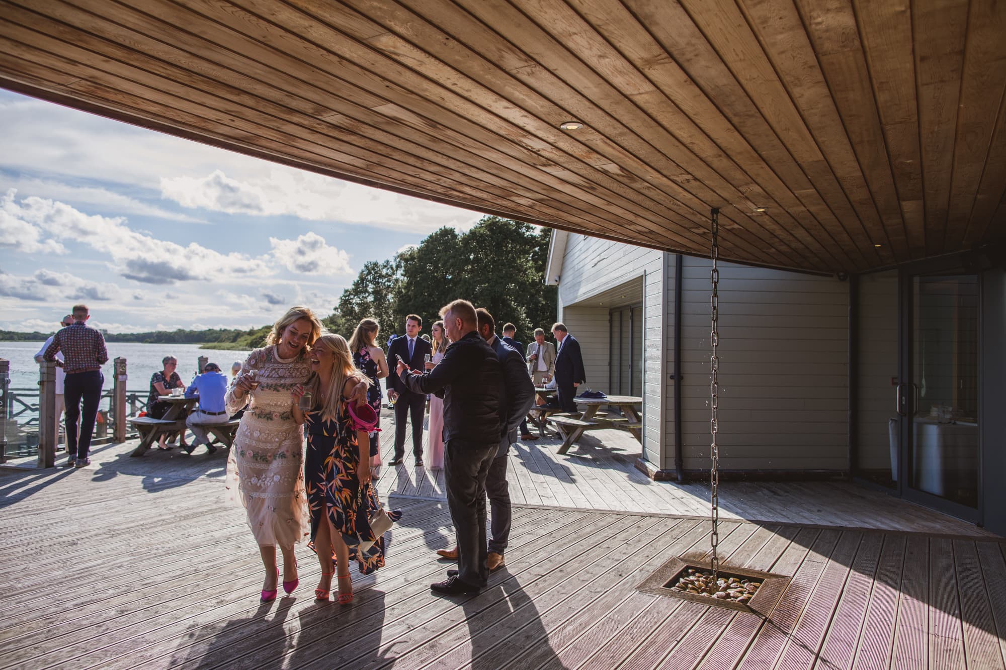 wedding guests drinking on the boathouse deck