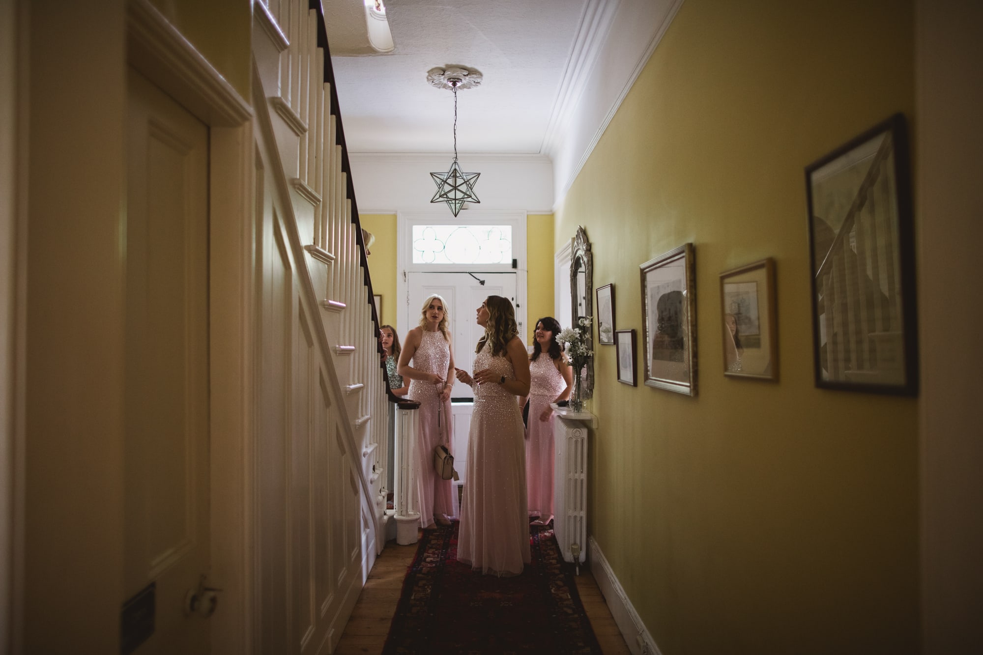 bridesmaids waiting at the bottom of the stairs for bride to make her appearance