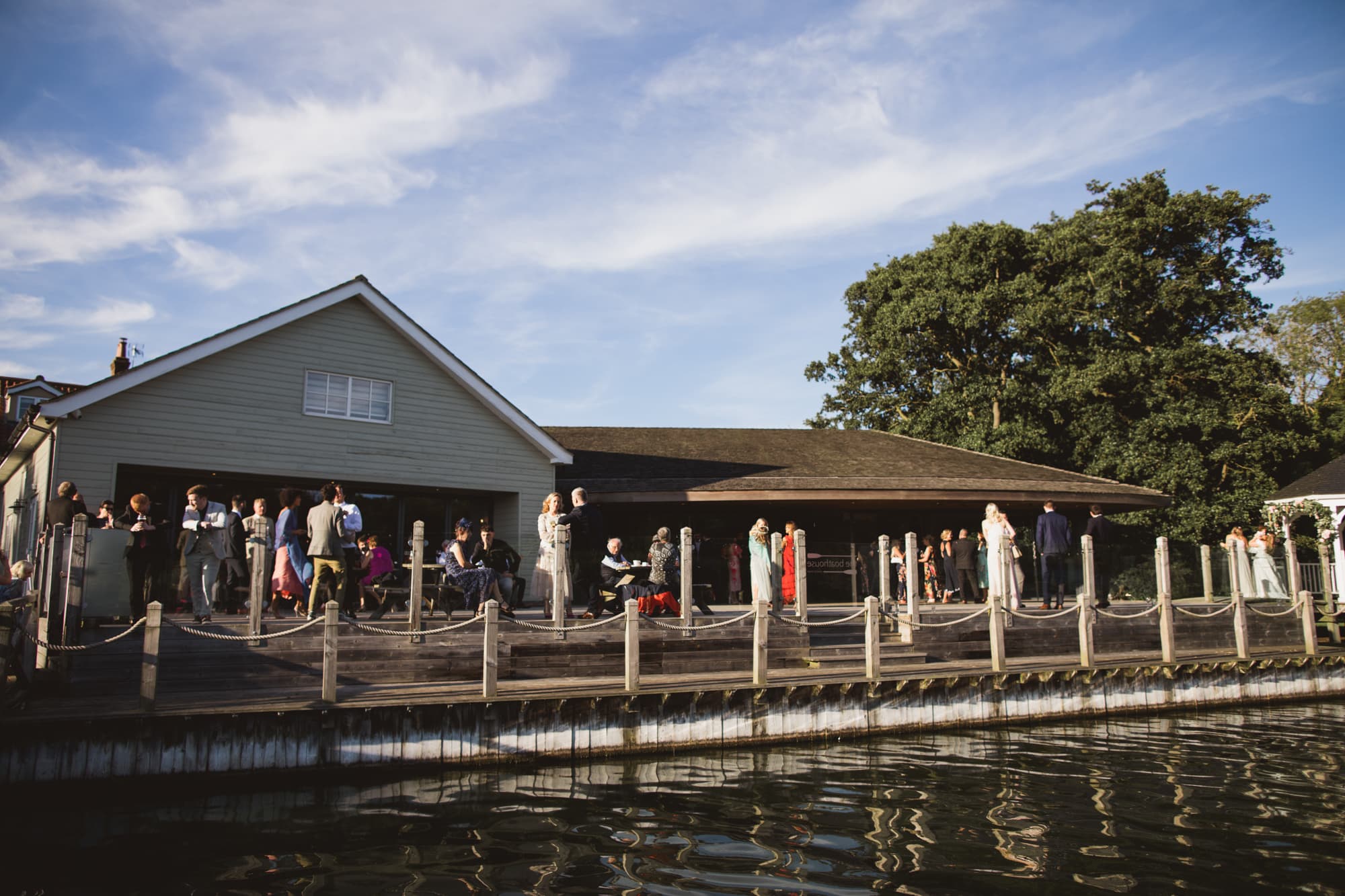 wedding guests enjoying drinks reception on the boathouse deck