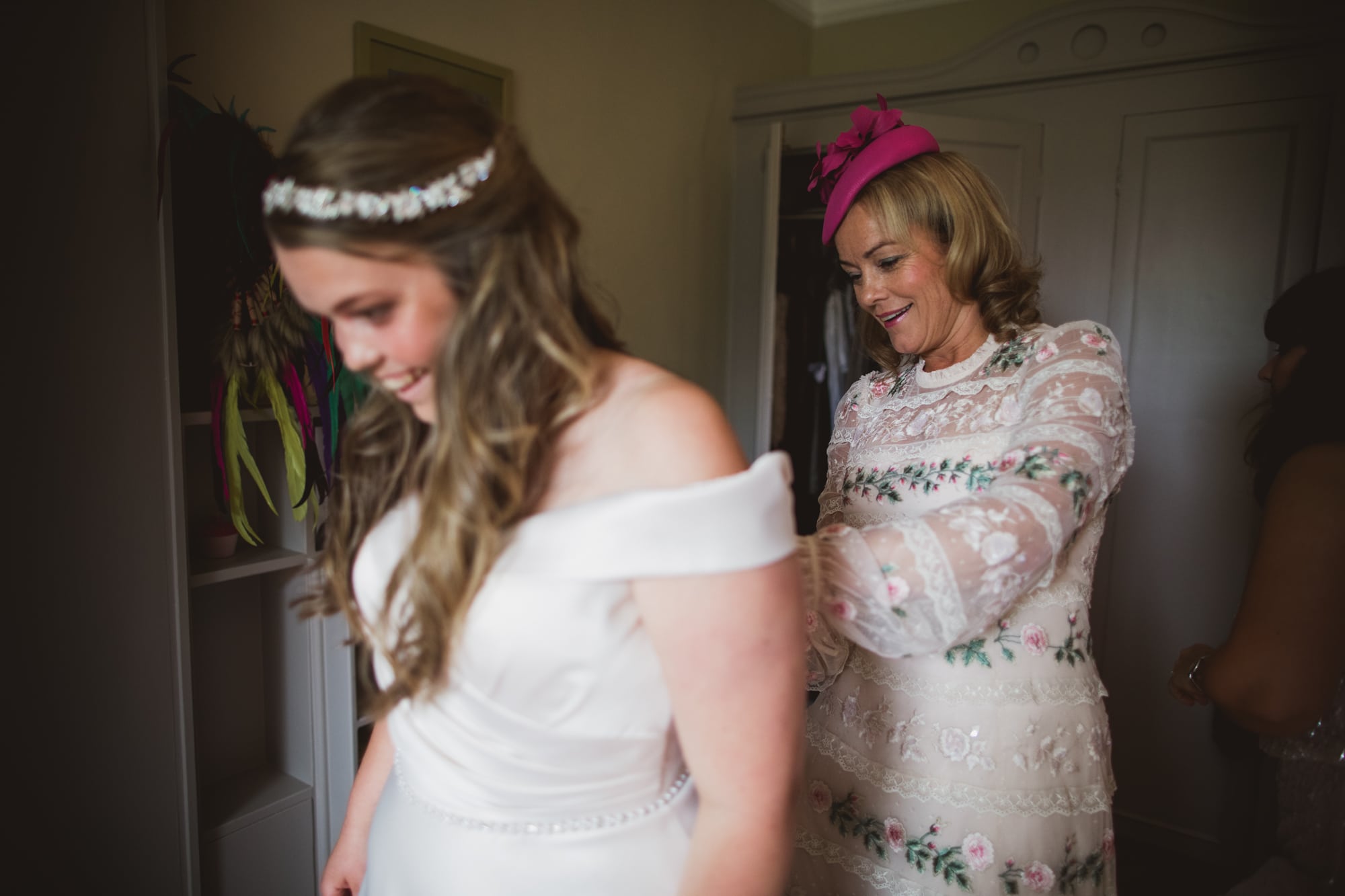 mum helping bride into wedding dress