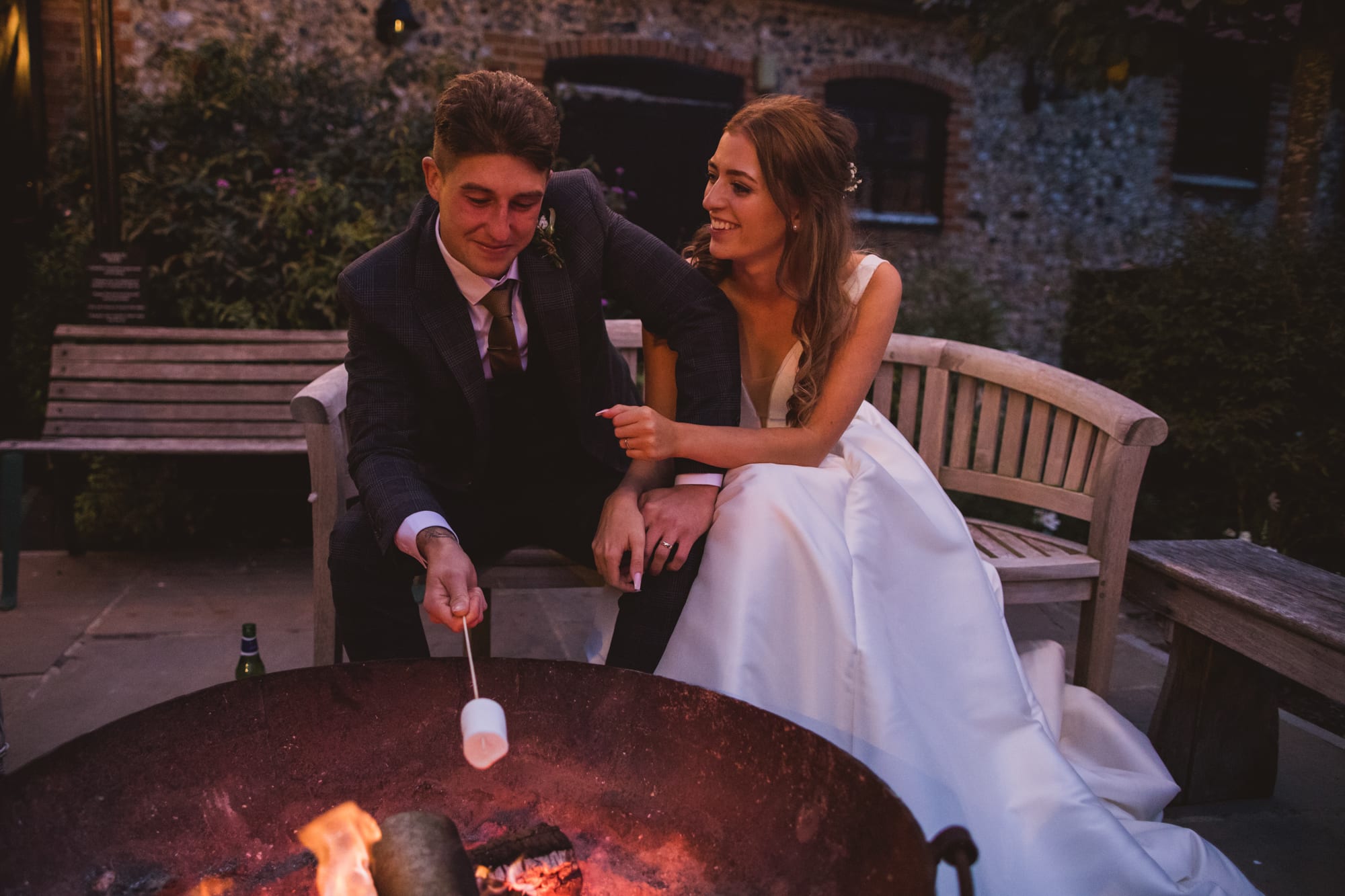 bride and groom with smores cooking over fire pit