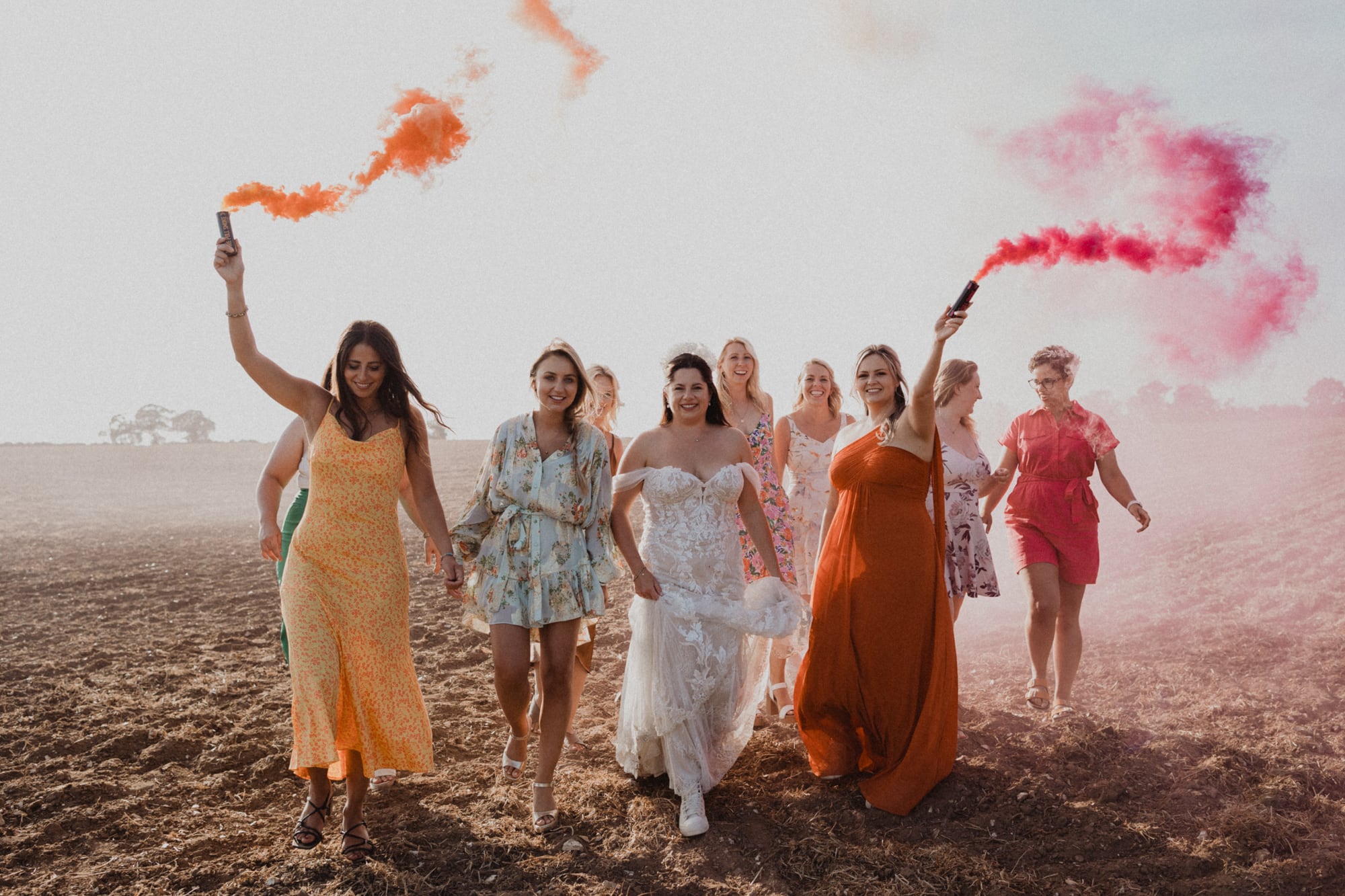 bride and friends with smoke bombs in field