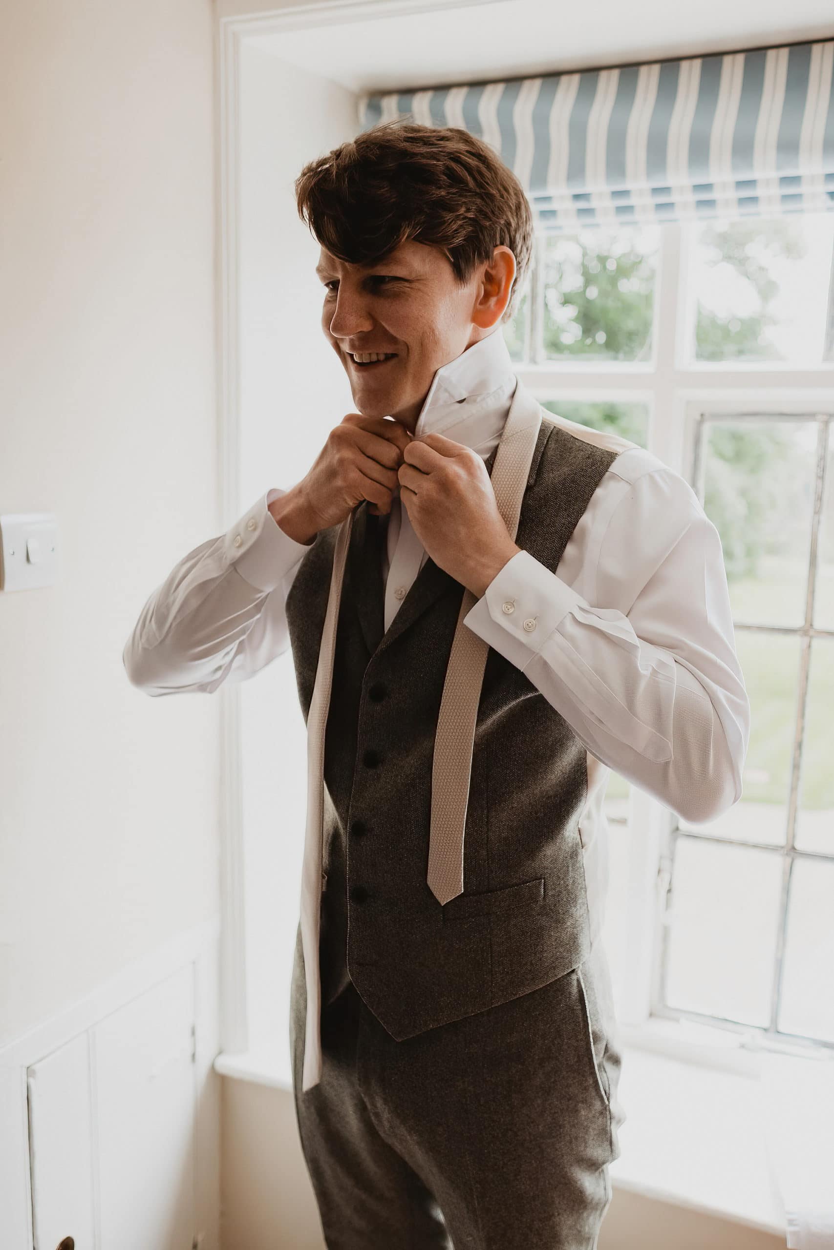 groom putting on shirt and tie