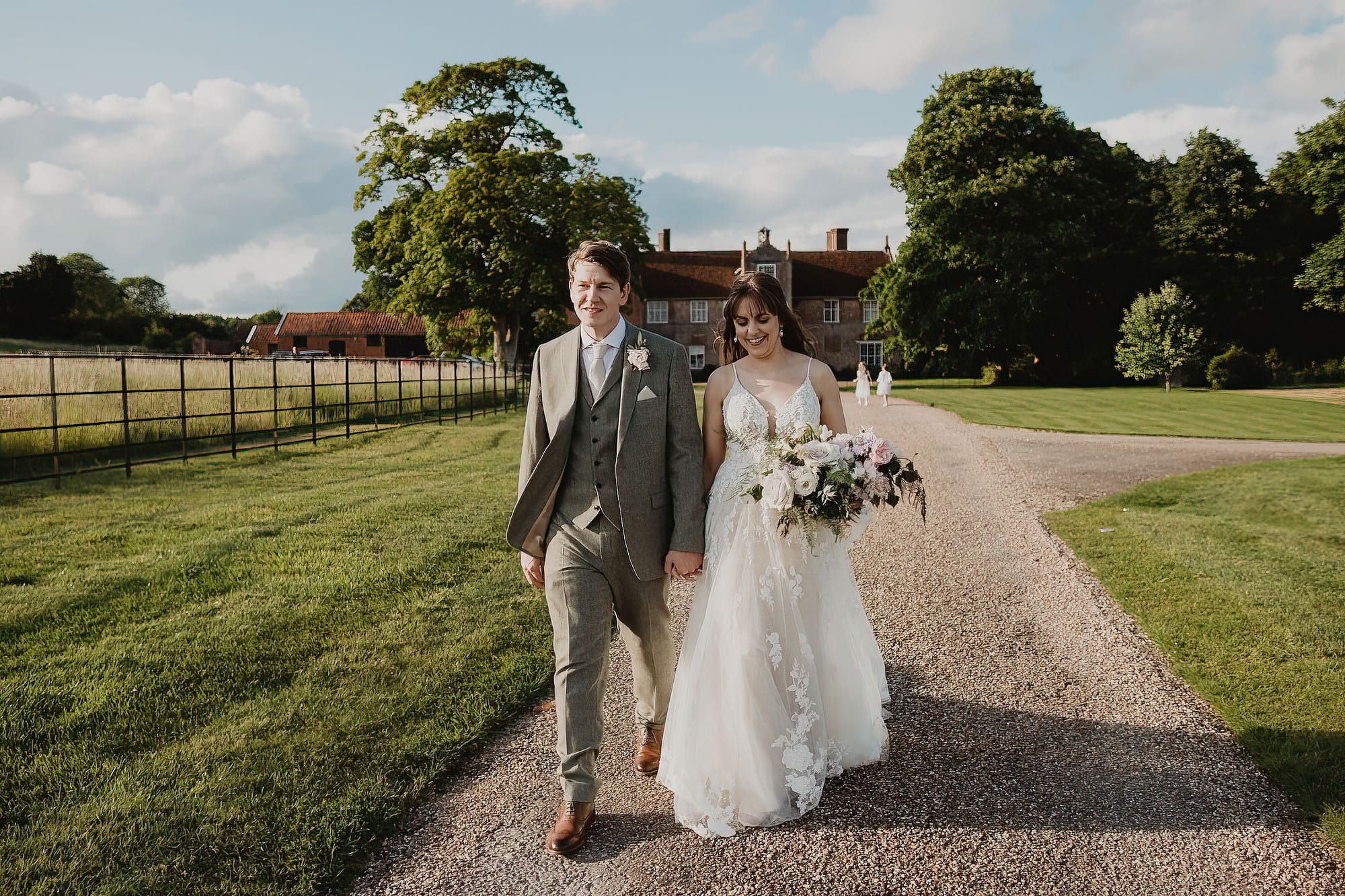 bride and groom walking along path in suffolk