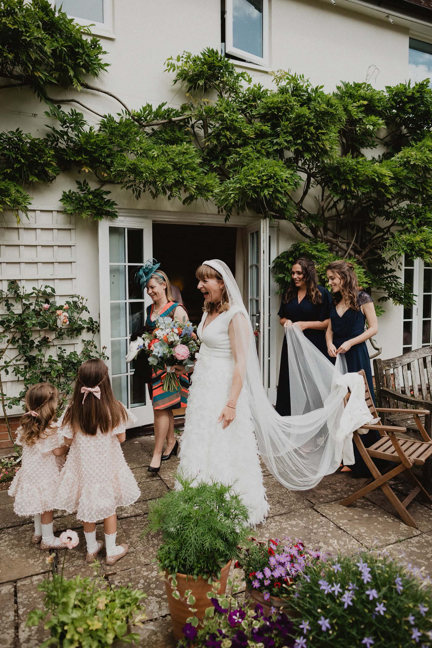 bride leaving her family home with her bridesmaids