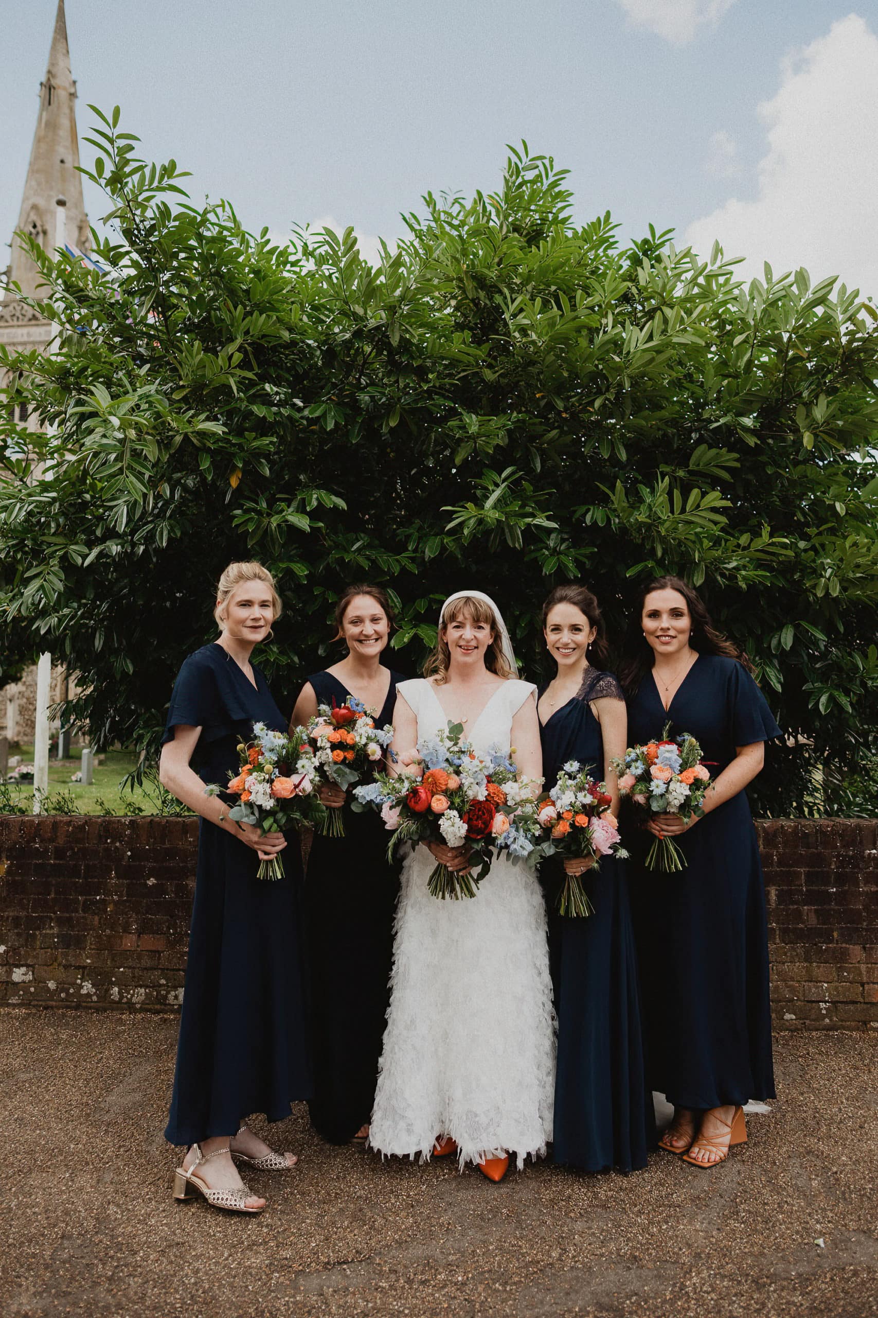 bride and bridesmaids posing in front of church for a photo