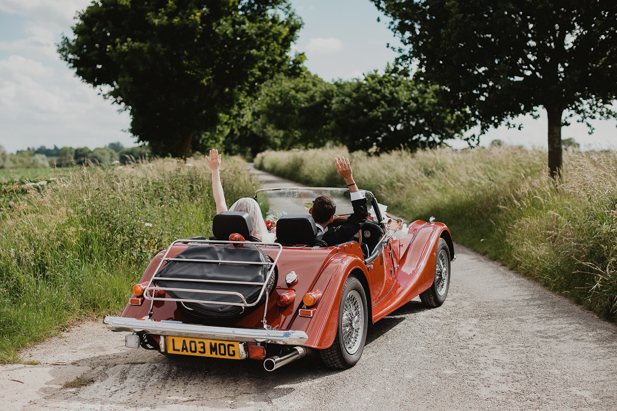 bride and groom in the suffolk countryside in a morgan