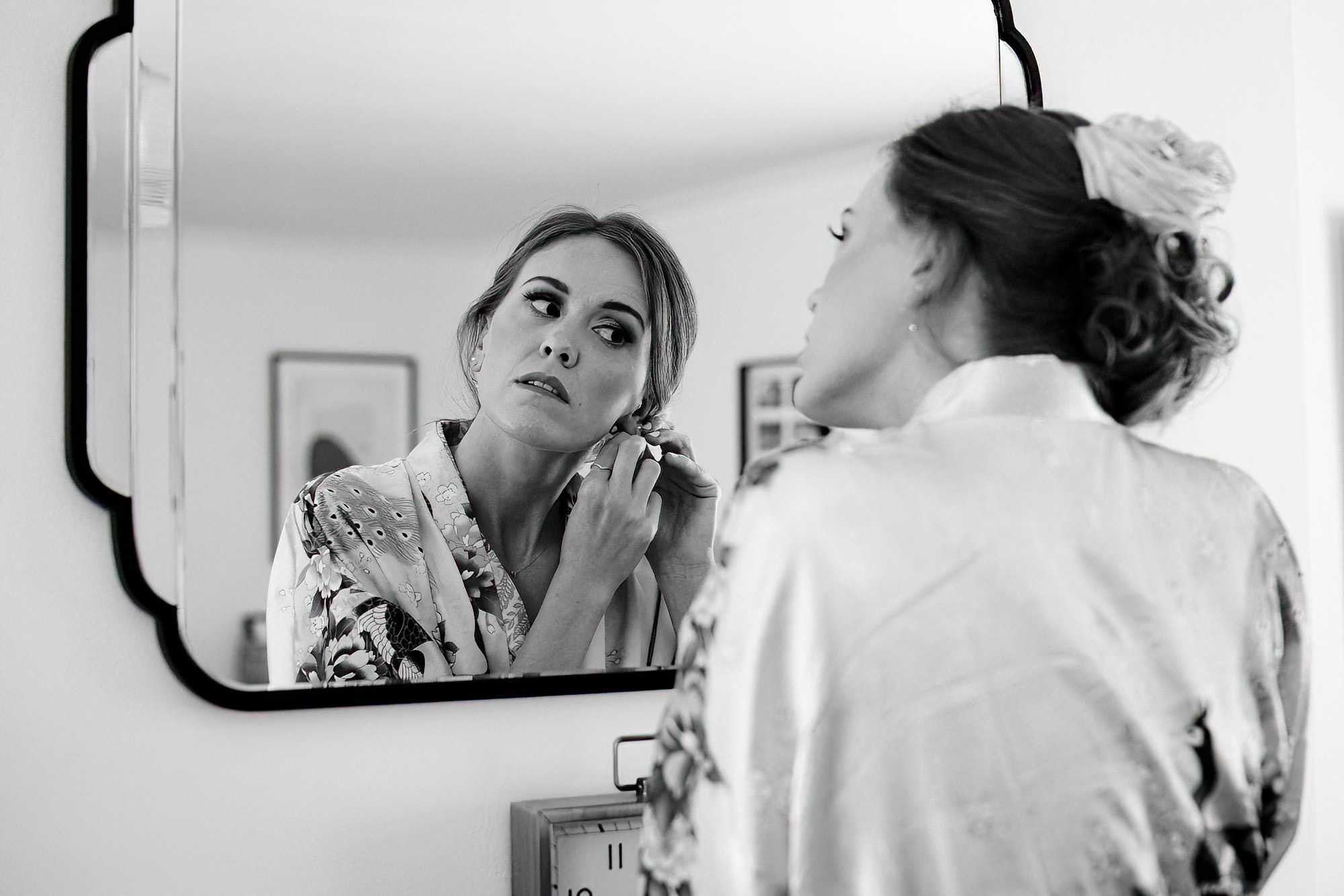 bridesmaid putting in earrings in front of mirror