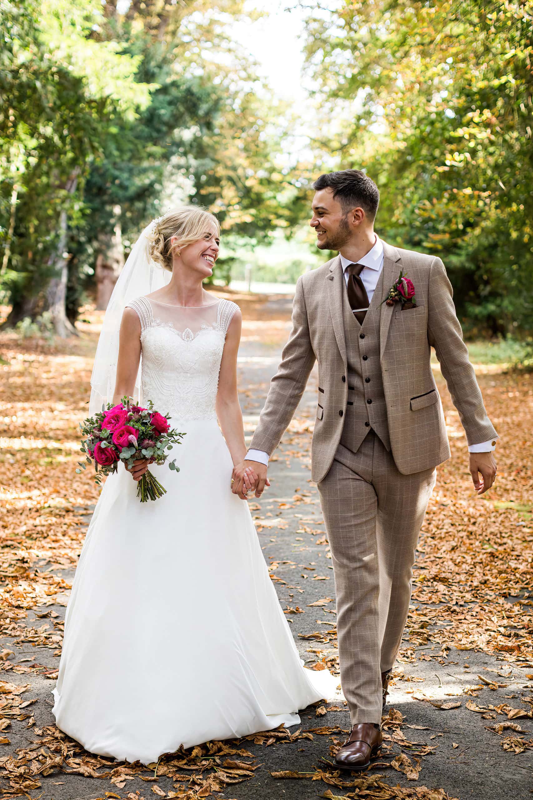 bride and groom walking along a leafy lane