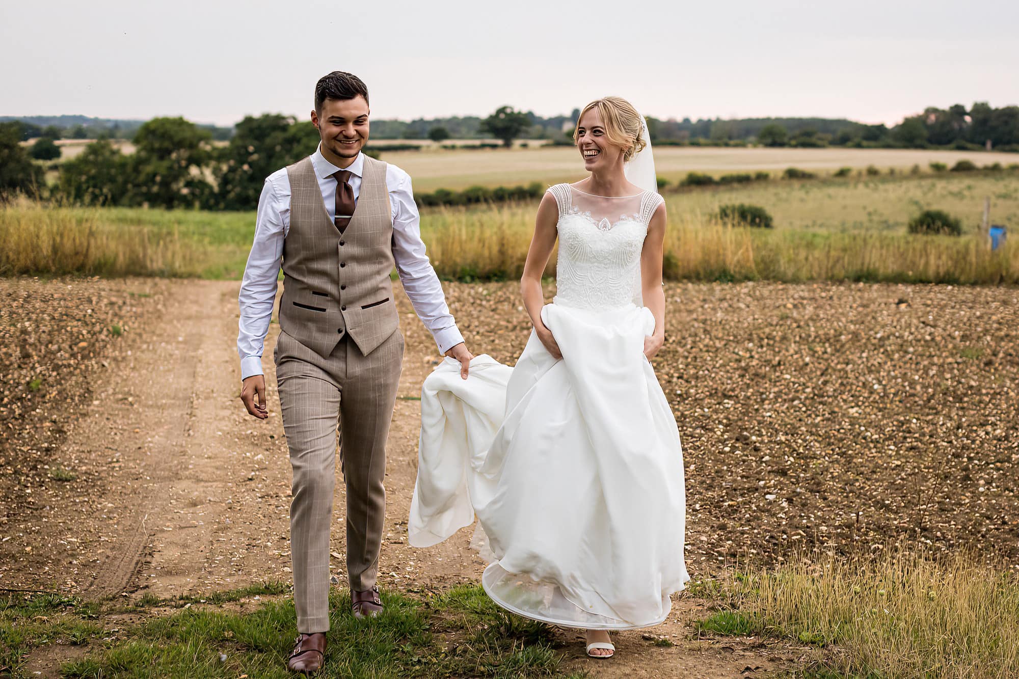 bride and groom walking across a field