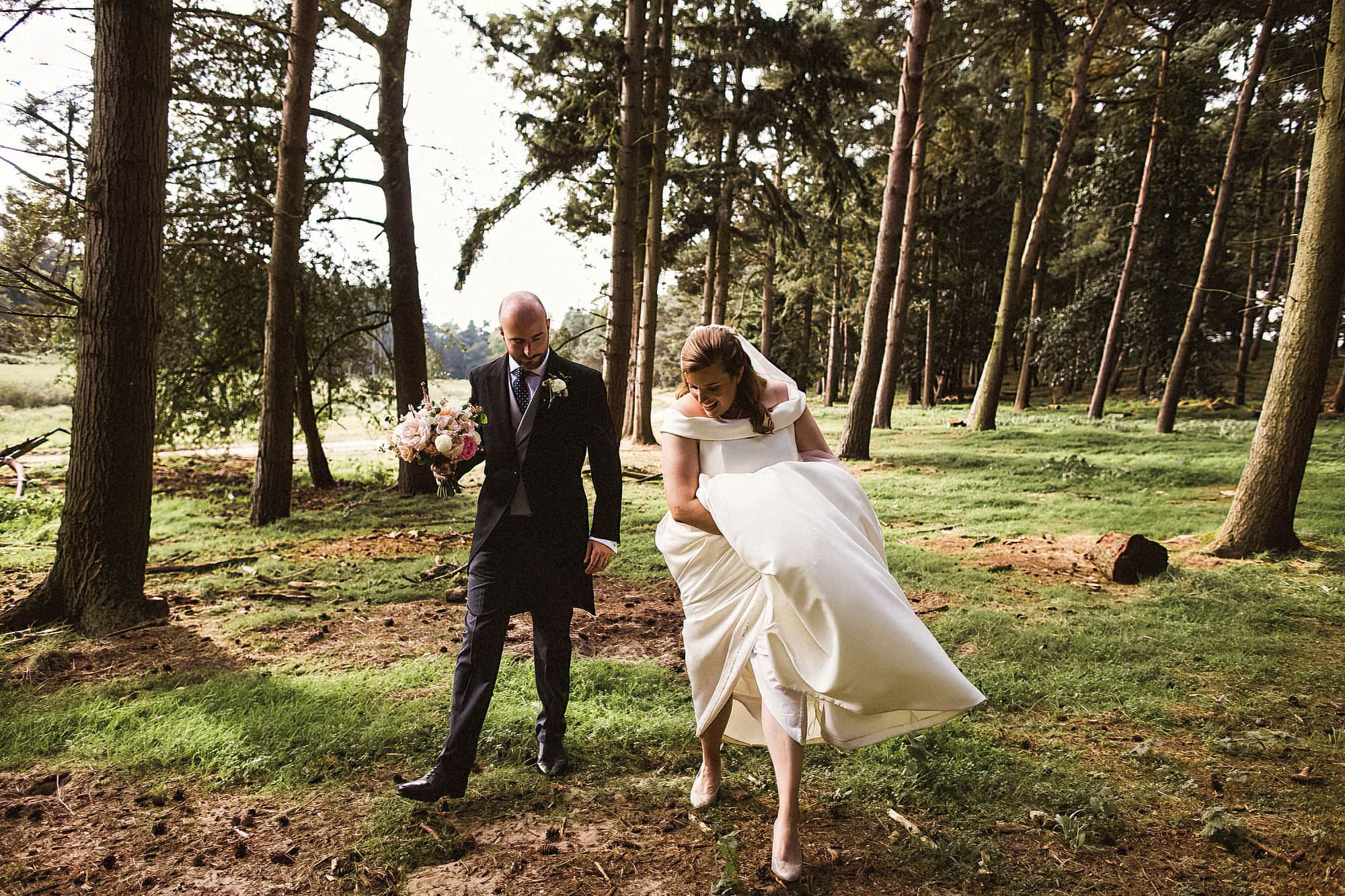 bride and groom walking through woodland at henham park