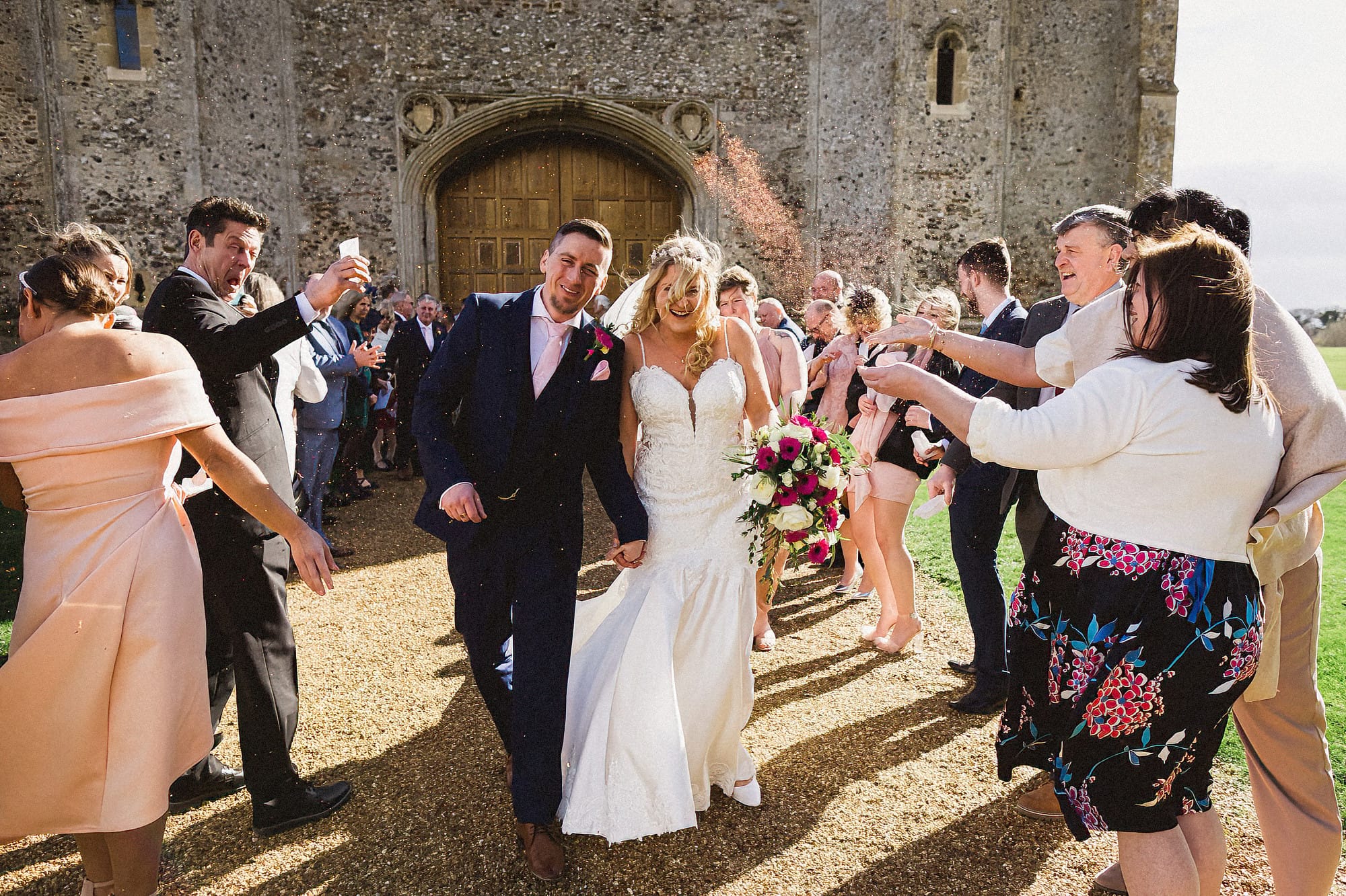 bride and groom walking through confetti at pentney abbey