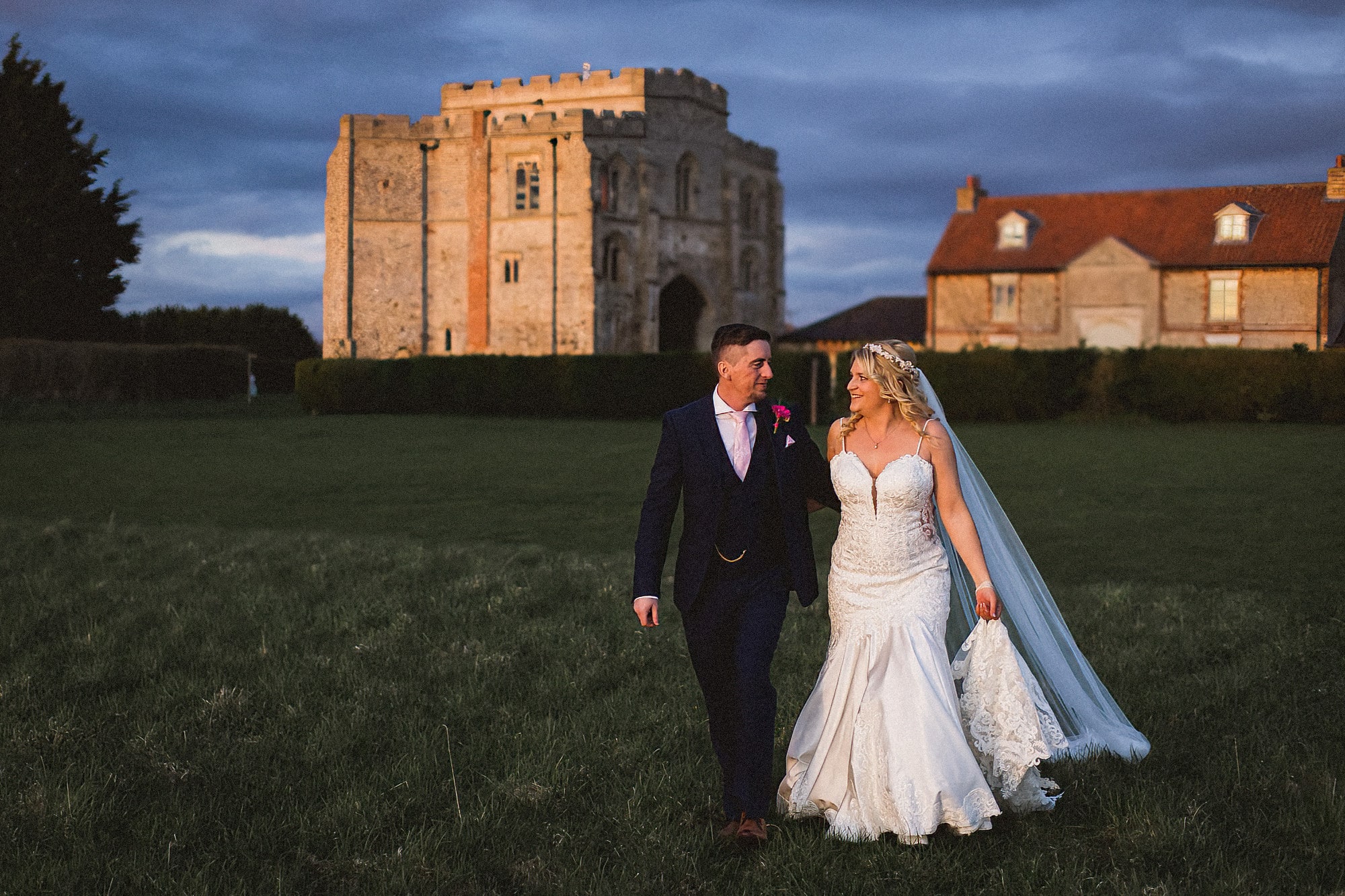 Bride and groom at sunset walking across the grounds at Pentney Abbey