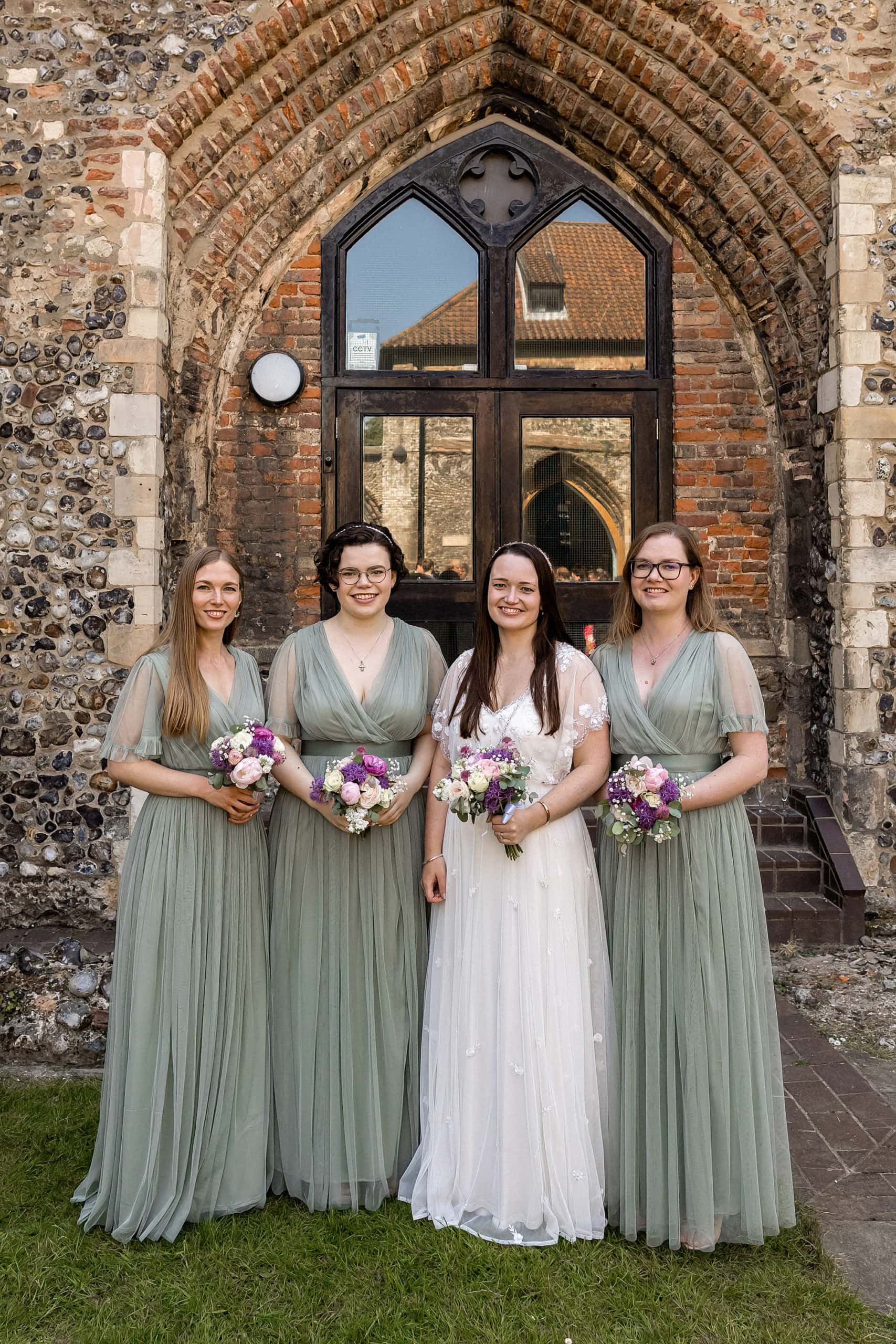 bride and bridesmaids wearing sage green dresses holding bouquets
