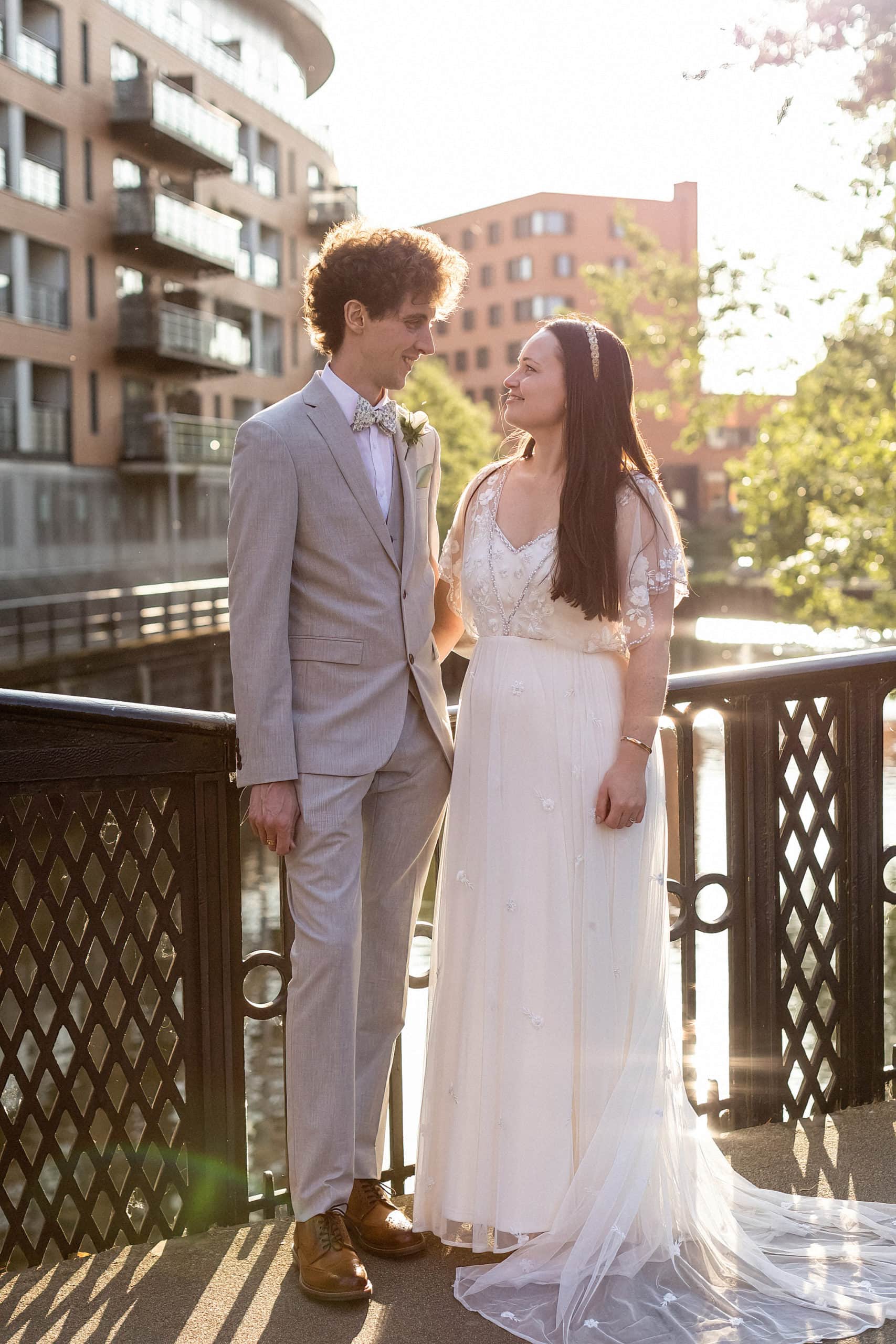 bride and groom standing on bridge in norwich posing for photo