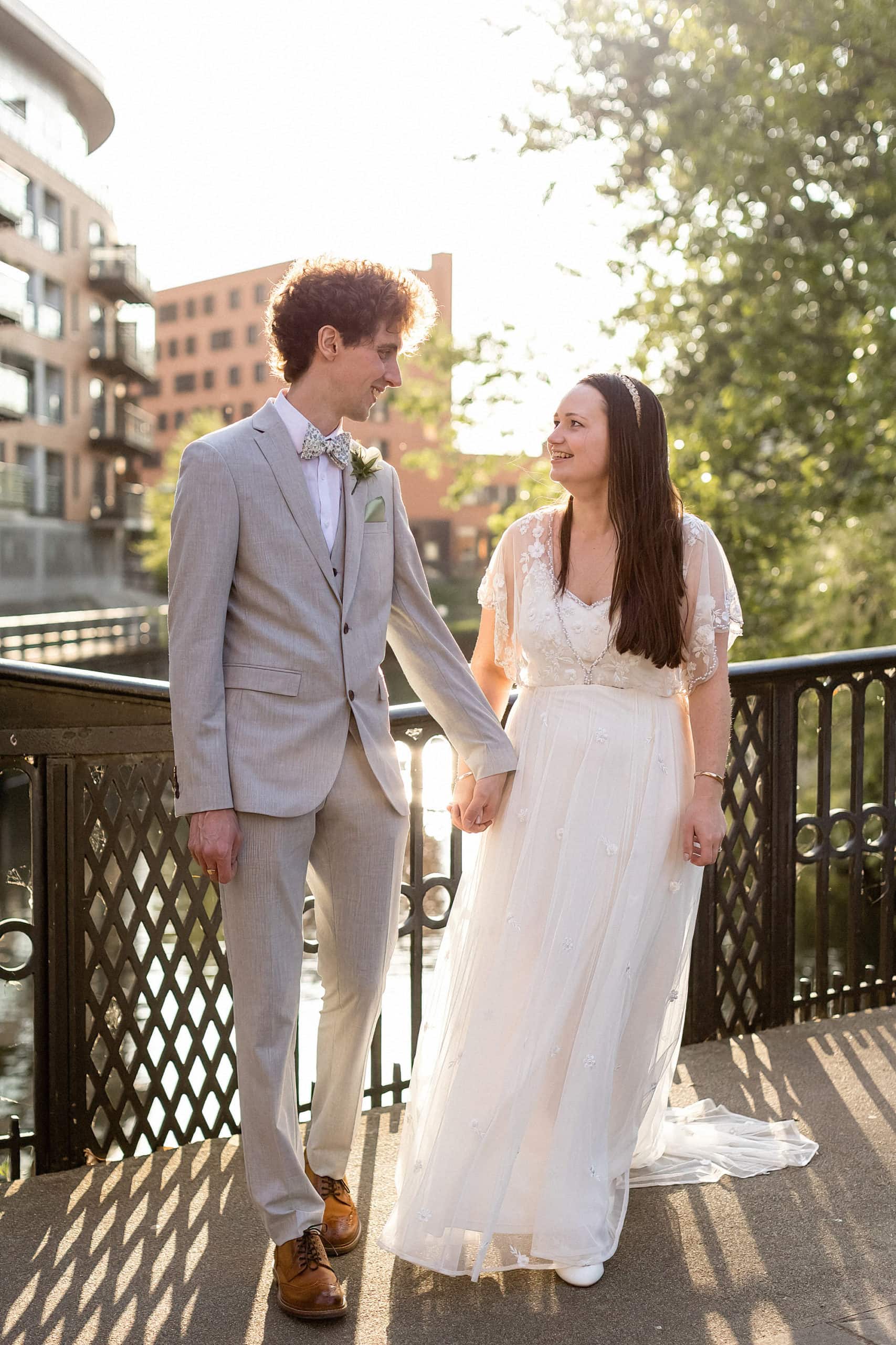 bride and groom standing on bridge in norwich posing for photo