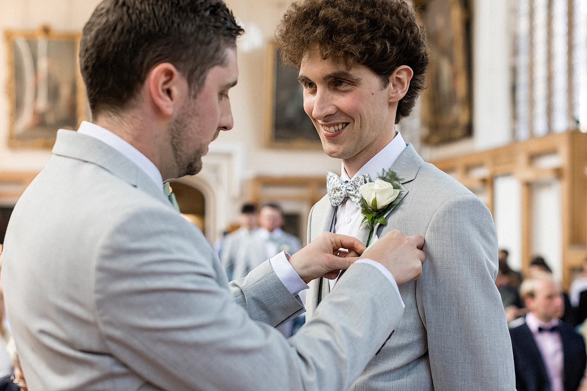 best man pinning button hole onto grooms jacket
