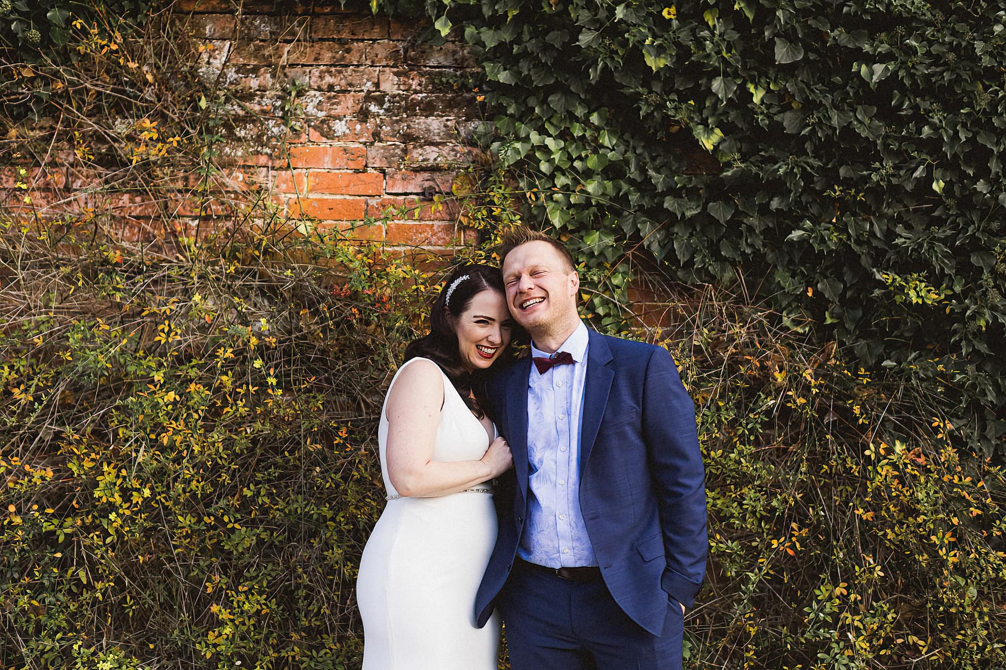 bride and groom standing in front of a wall at woodhall manor
