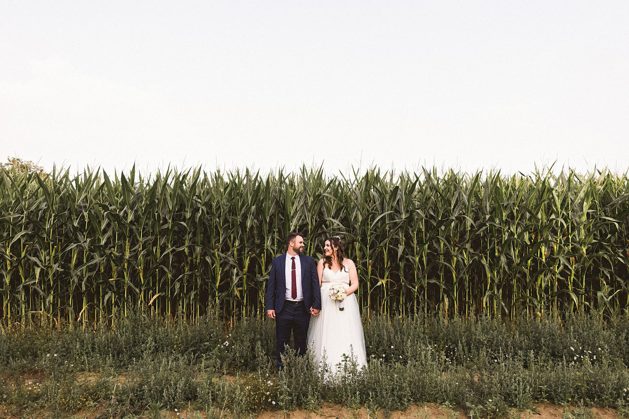bride and groom standing in front of maize