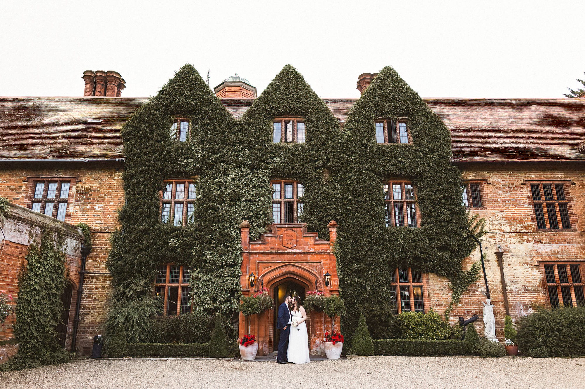 bride and groom standing in front of woodhall manor having a kiss