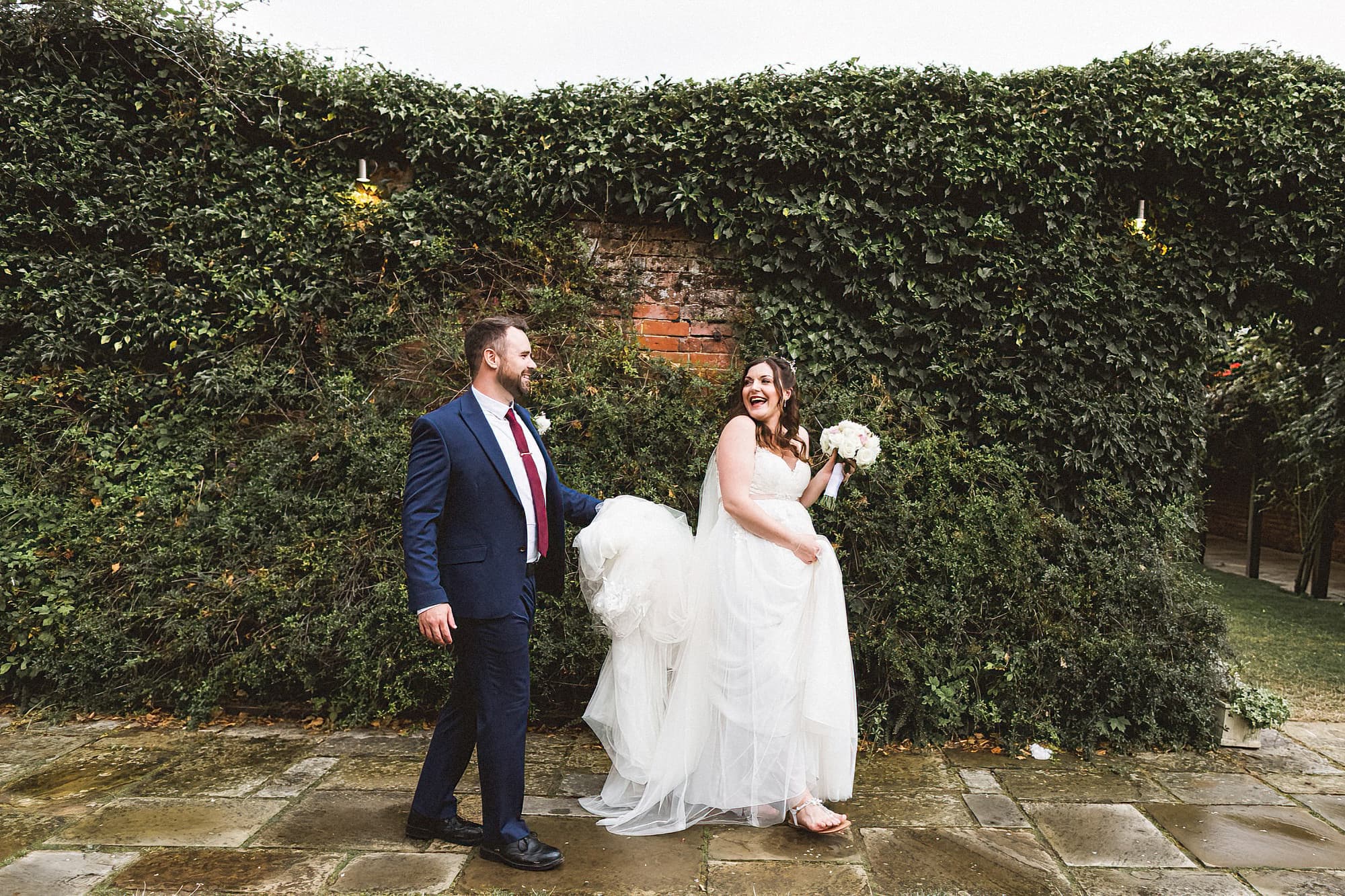 bride and groom walking across gardens at woodhall manor