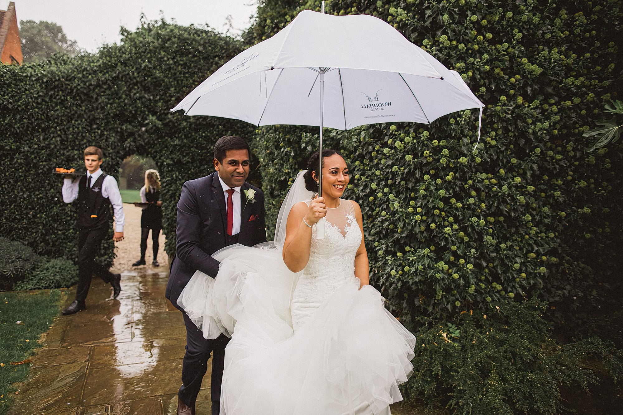 bride and groom walking in the rain with white umbrella
