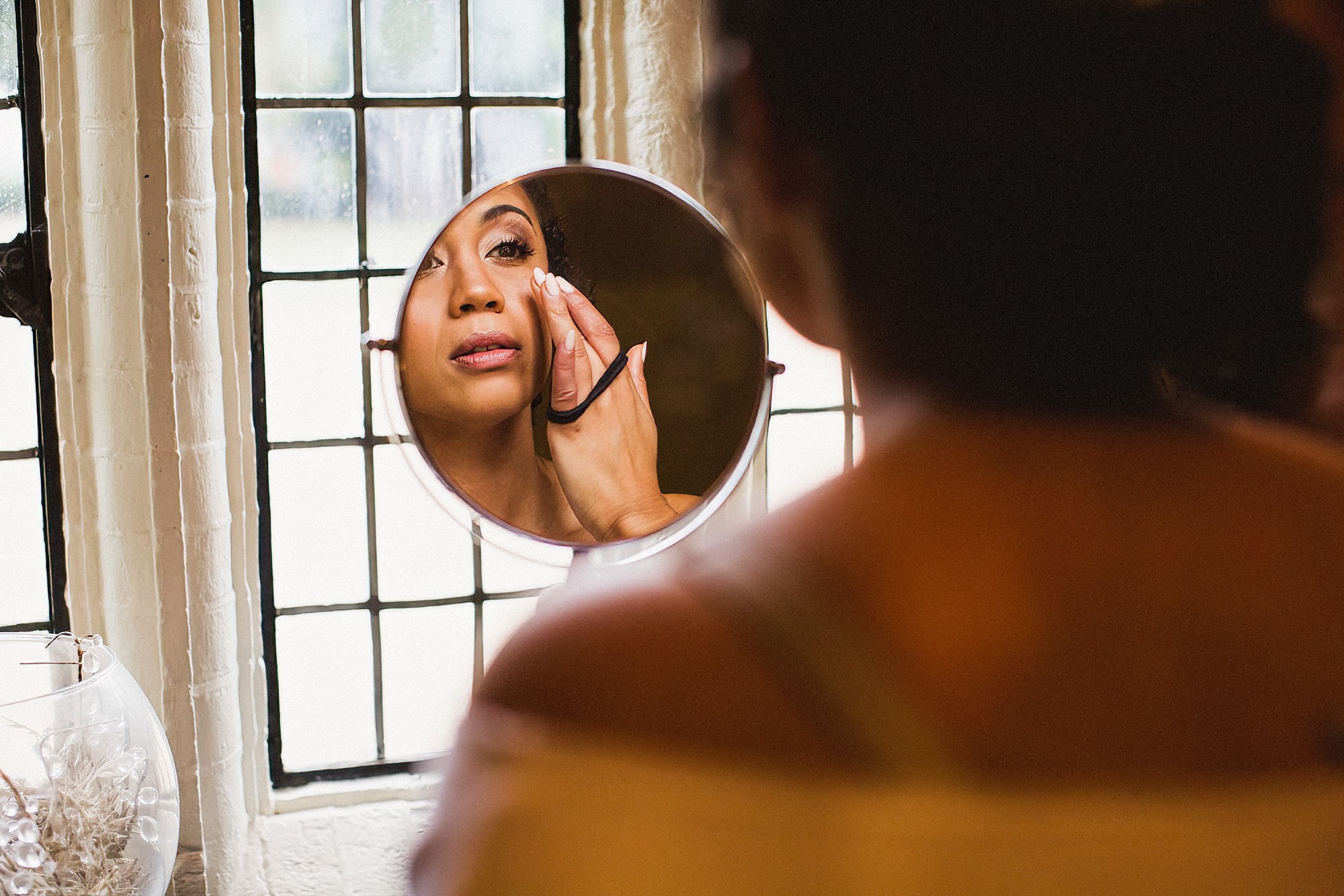 bride getting ready and looking in mirror putting on makeup